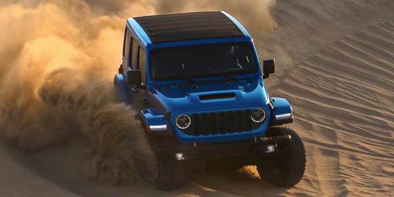 Blue Jeep Wrangler in desert dunes