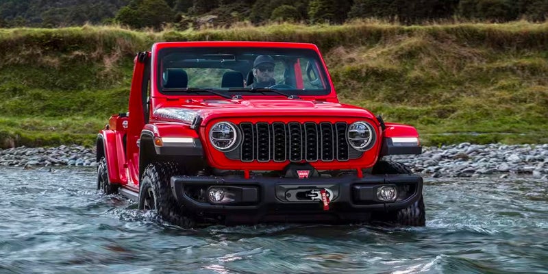 Red Jeep Wrangler crossing water