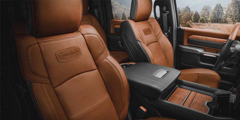 Luxurious truck interior with tan leather seats featuring Longhorn embossing, wood trim, and a black center console.