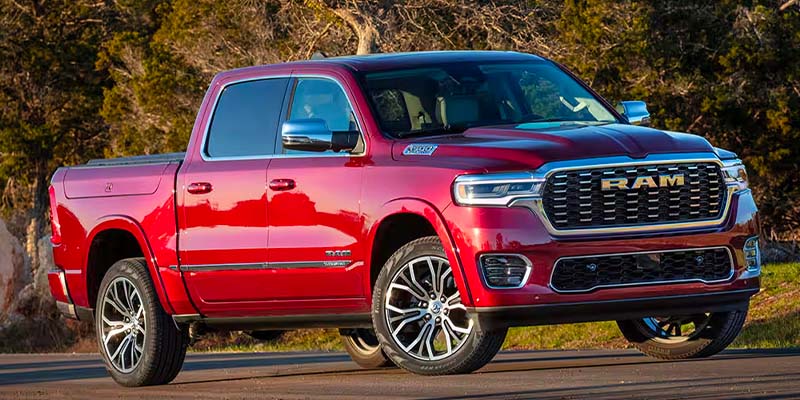 A shiny red Ram pickup truck with a large chrome grille and distinctive headlights, parked outdoors.