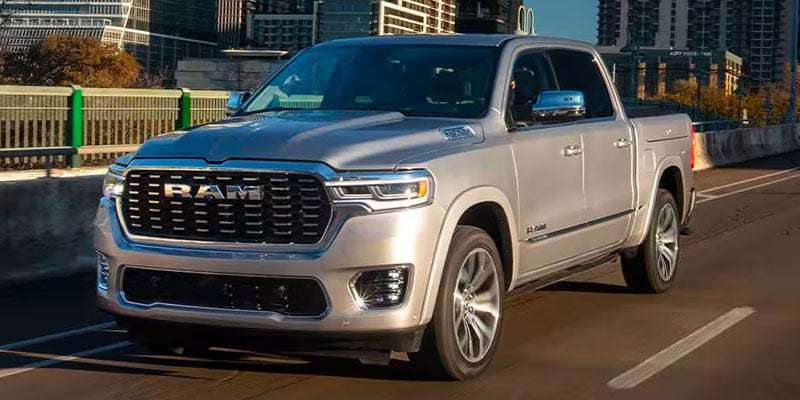 Gray 2022 Ram 1500 Limited pickup truck driving on a multi-lane city highway at dusk.