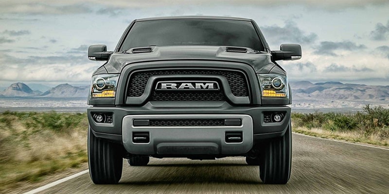 Front view of a dark gray Ram truck with a black grille and silver bumper on a highway.