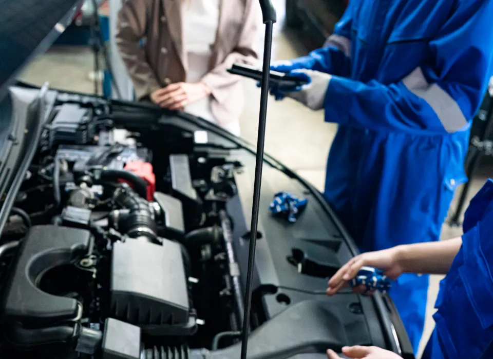 service person working under the hood of a car